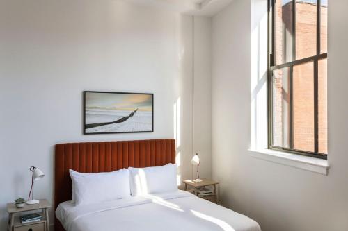 um quarto branco com uma cama e uma janela em ROOST Cleveland em Cleveland