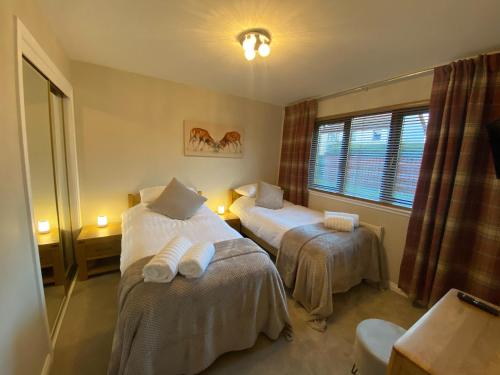 Habitación de hotel con 2 camas y ventana en discoverNESS Apartment, en Inverness