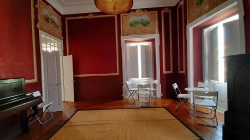 a room with red walls and chairs and a piano at A Casa do Tenente in Faro