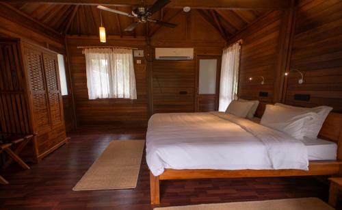 a bedroom with a large bed in a wooden room at Big Tree Cottages in Beadonābād