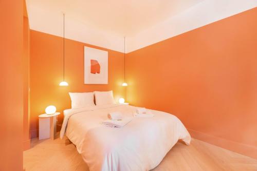 a bedroom with a white bed with orange walls at Jardim Suites by Olala Homes in Cascais