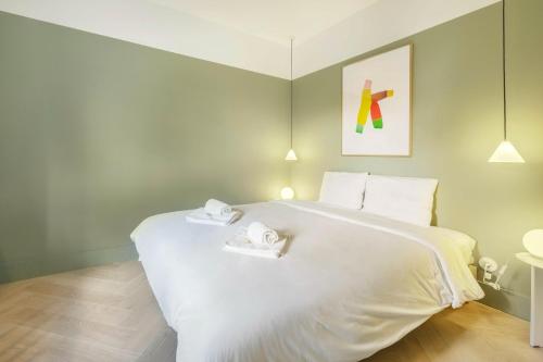 1 dormitorio con 1 cama blanca grande y 2 toallas en Jardim Suites by Olala Homes, en Cascais