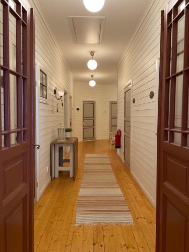 a hallway with wooden floors and white walls and a door at Bashults Gård in Jönköping