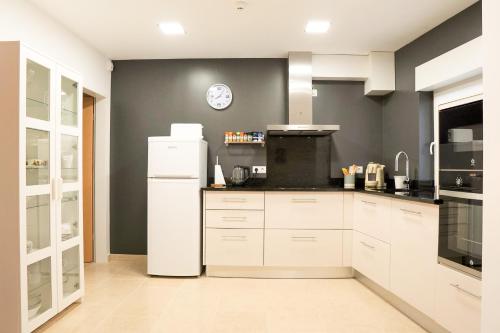 a kitchen with a white refrigerator and a clock on the wall at Modernes Haus mit spektakulärem Meerblick und Pool in Vale Furado