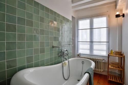 La salle de bains est pourvue d'une baignoire et d'un mur carrelé vert. dans l'établissement Les Oiseaux du Corsaire 3 House & Terrace 6 P - Center Honfleur, à Honfleur