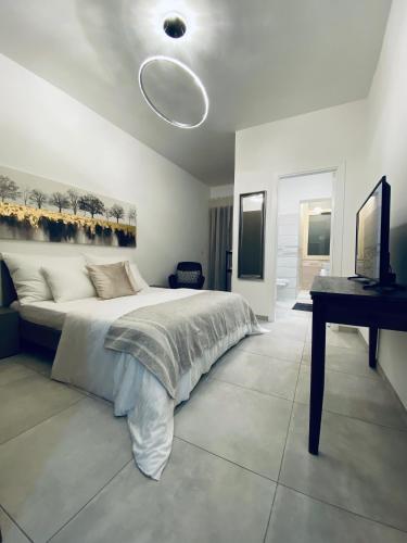 a white bedroom with a bed and a desk at Regina in Tropea