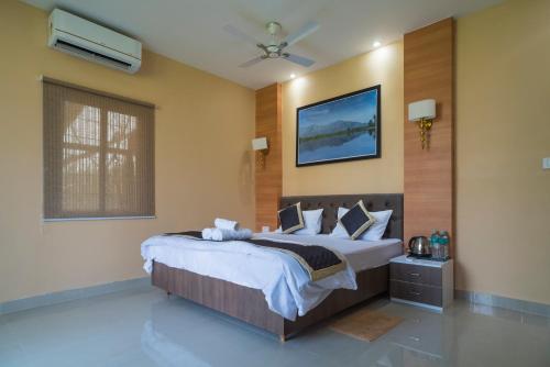 - une chambre avec un grand lit et un ventilateur de plafond dans l'établissement Tusker Tea County, à Chālsa Mahābāri