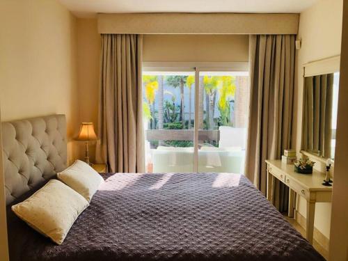 een slaapkamer met een bed en uitzicht op een patio bij Beachside Luxury 2 bedroom apartment, Puerto Banus in Marbella