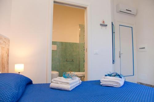 a bedroom with a blue bed with towels on it at Le Cale in Trapani