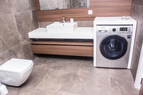 a bathroom with a washing machine and a sink at Accra Luxury Apartments @ Pearl in Accra