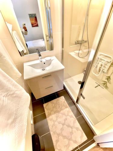 une petite salle de bain avec un lavabo et une douche dans l'établissement Etretat: agréable maison de ville, à Étretat