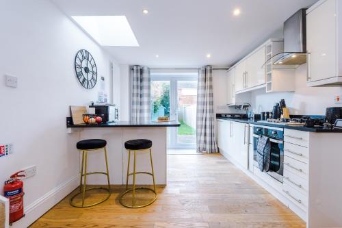 a kitchen with two stools in a kitchen with a clock on the wall at Pristine 2-bed house in Chester by 53 Degrees Property, ideal for Families & Small groups, Great Location - Sleeps 6 in Hough Green