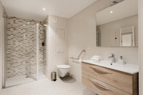 a bathroom with a shower and a toilet and a sink at Edgar Suites Châtillon in Châtillon