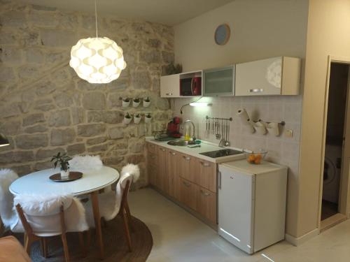 a kitchen with a table and a stone wall at Leut Apartment in Korčula