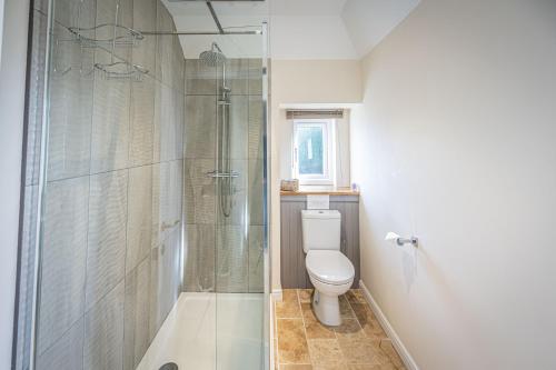 a bathroom with a toilet and a glass shower at Cliff Walk Cottage in Arbroath