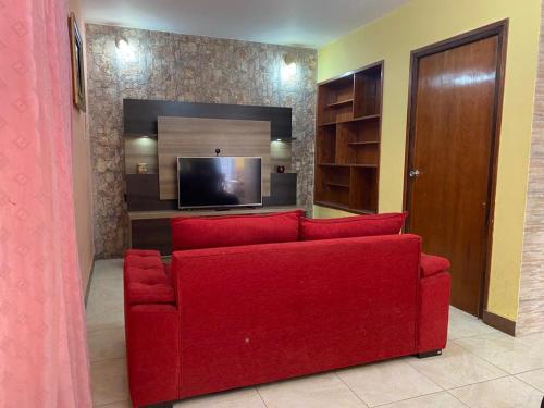 un sofá rojo en la sala de estar con TV en La Casa de Los Sueños en San Juan