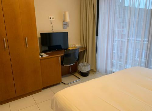 a hotel room with a bed and a desk with a television at Hotel De Croone in Ninove