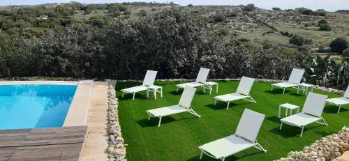 a group of white chairs and a swimming pool at SAN MARTIN WELLNESS RETREAT (Upper) in Il-Palma