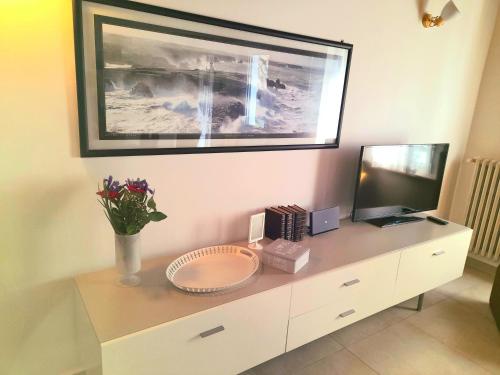 a white cabinet with a television and flowers on it at Les Amis in Peschiera del Garda