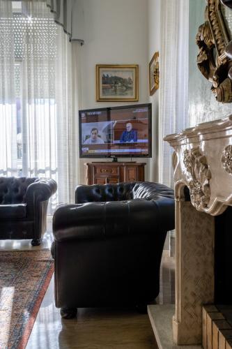 a living room with a black leather couch and a television at Esedra Hotel in Rimini