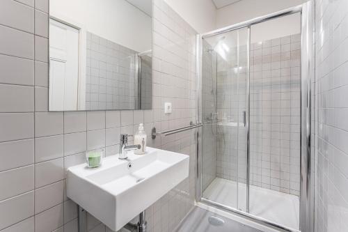 een witte badkamer met een wastafel en een douche bij GuestReady - Costa Cabral Guesthouse Room 4 in Porto