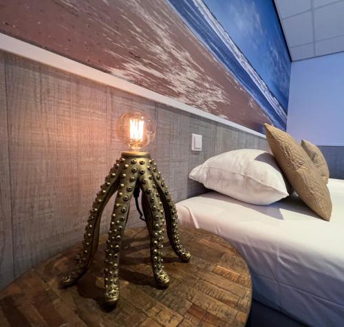 a bedroom with a bed with a lamp on a table at SEA YOU Hotel Noordwijk in Noordwijk aan Zee