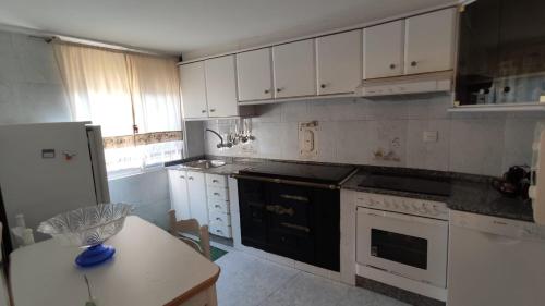 a kitchen with white cabinets and a black stove top oven at A casa do teléfono in Pumares