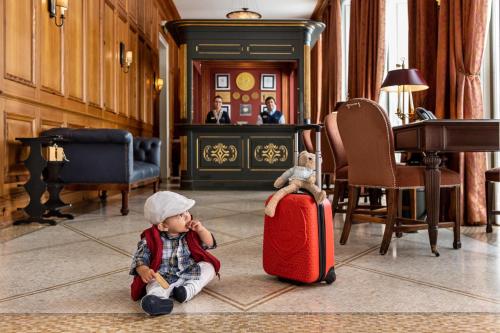a little boy sitting on the floor with a suitcase at Vidago Palace in Vidago