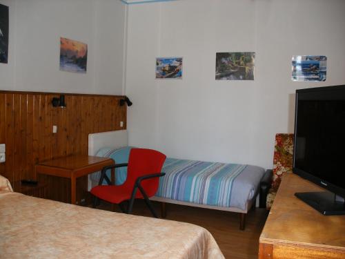 a room with a bedroom with a bed and a red chair at Hôtel Modern in Concarneau
