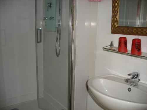 a white bathroom with a shower and a sink at Hôtel Modern in Concarneau