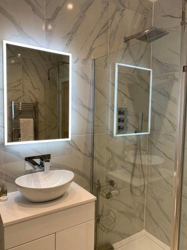 a bathroom with a sink and a shower with a mirror at Postmans Rest, second floor apartment, Lynmouth with private parking in Lynmouth