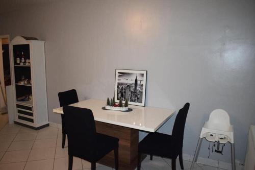 une salle à manger avec une table et des chaises blanches dans l'établissement Le gîte de la palmeraie, à Étauliers