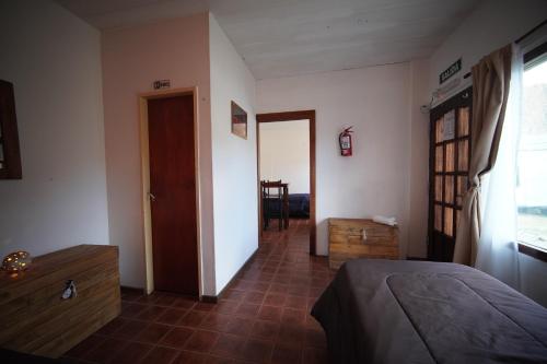 Un dormitorio con una cama y un pasillo con una puerta. en Magna, en El Chaltén