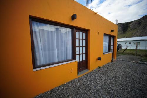 an orange building with a window with a white curtain at Magna in El Chalten