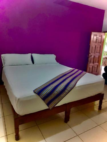 a bed in a room with a purple wall at Casa “Doña Zoyla” B&B in Copan Ruinas