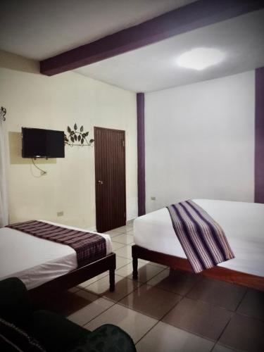 a hotel room with two beds and a flat screen tv at Casa “Doña Zoyla” B&B in Copan Ruinas