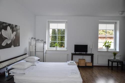 a white bedroom with a bed and two windows at Vęgoria 17 Apartament przy porcie in Węgorzewo