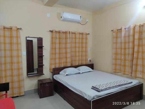 een slaapkamer met een bed, een spiegel en gordijnen bij KASAHARA - HOMESTAY in Bolpur