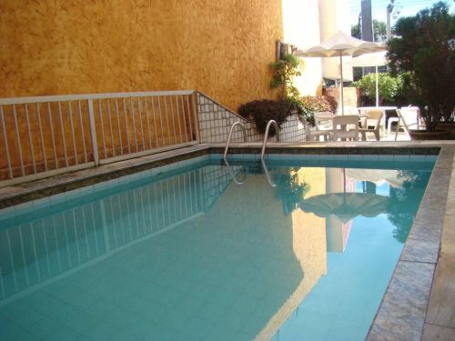 a swimming pool with a table and an umbrella at Raio de Sol Praia Hotel in Fortaleza