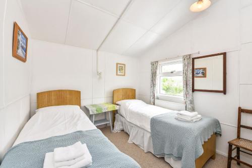 a twin bedroom with two beds and a window at Seasidings, Pagham in Pagham