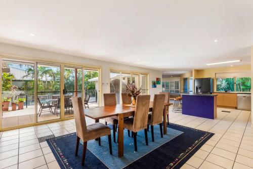 a kitchen and dining room with a wooden table and chairs at Frangipani Hideaway in Lennox Head