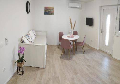 um quarto branco com uma mesa e cadeiras, uma mesa e uma mesa em Apartments Anamarija em Zadar