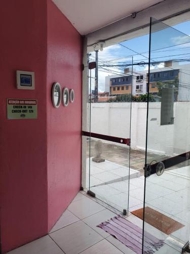 a room with a pink wall and a glass door at Casa da Esquina Pousada in Recife