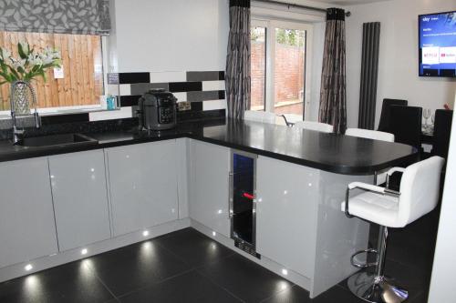a kitchen with a black counter top and white chairs at 4 Bedroom Detached Holiday home with Hot Tub in Wrexham