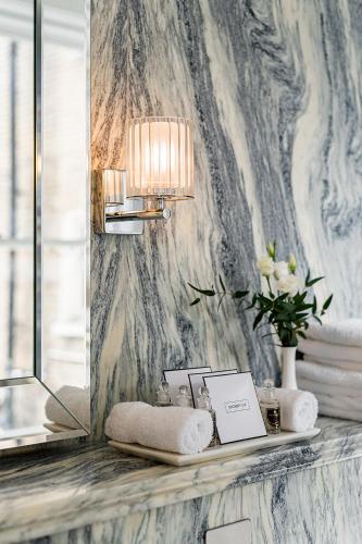 a bathroom with a mirror and a shelf with towels at The Adria in London