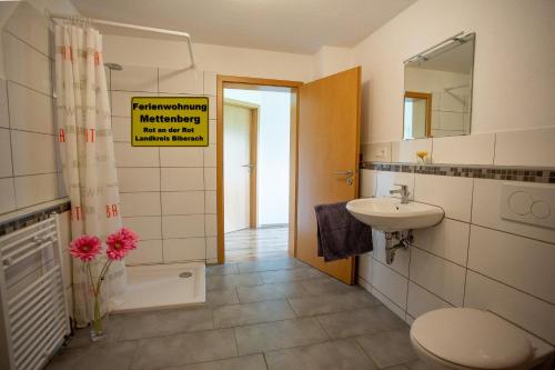 ein Badezimmer mit einem Waschbecken, einem WC und einem Spiegel in der Unterkunft Ferienwohnung Mettenberg in Rot an der Rot
