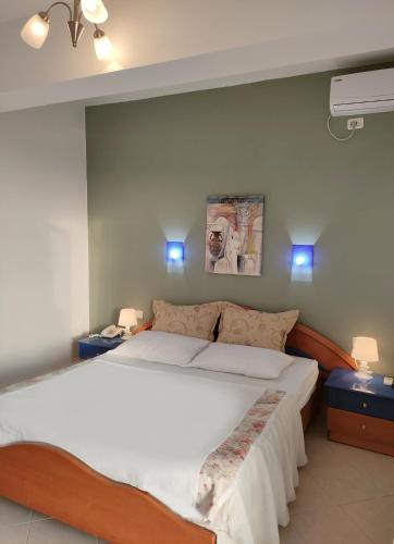a bedroom with a large white bed with blue lights at Olympia Hotel in Sarandë