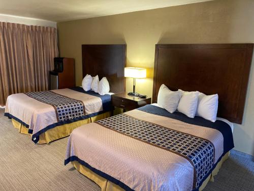 a hotel room with two beds and a lamp at Vino Inn & Suites in Atascadero