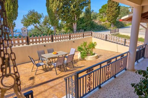 een patio met een tafel en stoelen en een hek bij Villa Christine Afionas Corfu in Afionas
