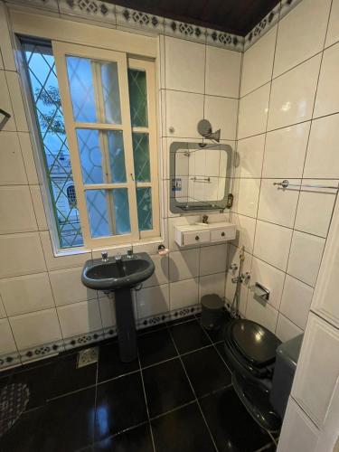 a bathroom with a sink and a mirror and a toilet at Casa Moinhos de Vento Vintage in Porto Alegre